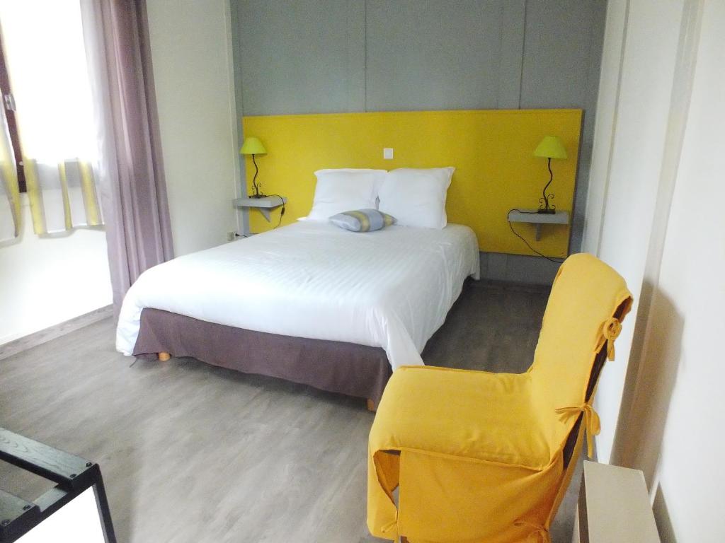 um quarto com uma cama grande e uma cadeira amarela em Hotel Restaurant Le Manguier em Peyrat-de-Bellac