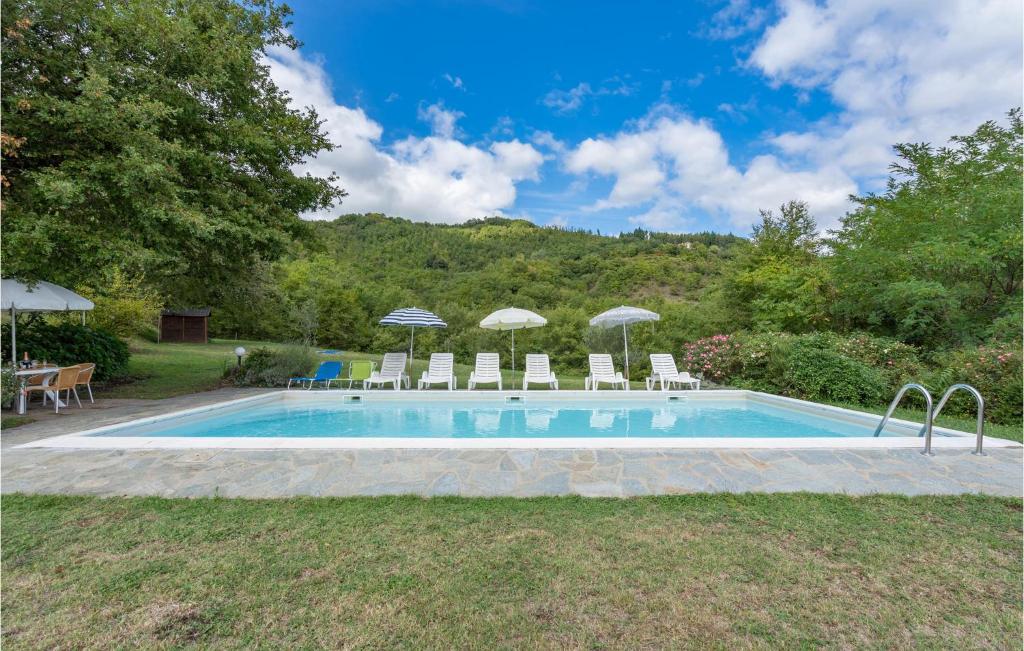 a swimming pool with chairs and umbrellas in a yard at Nice Home In Dicomano Fi With 4 Bedrooms, Private Swimming Pool And Wifi in Villore