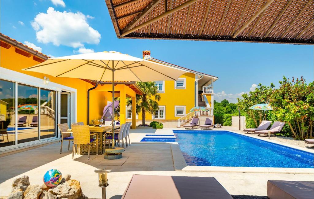- une terrasse avec une table et un parasol à côté de la piscine dans l'établissement Cozy Apartment In Labin With Wifi, à Labin