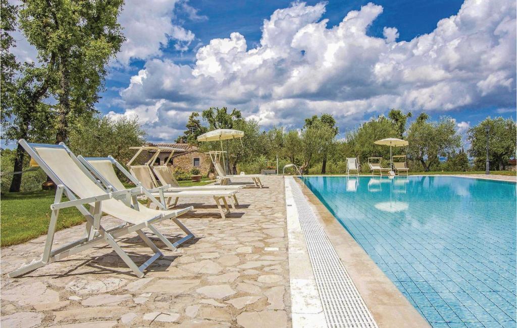 a swimming pool with chairs and umbrellas next to a swimming pool at Sangiovese 3 in San Donato in Poggio