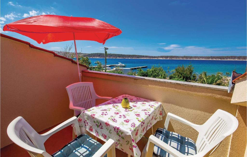a table and chairs on a balcony with a red umbrella at Nice Apartment In Rab With Kitchen in Rab