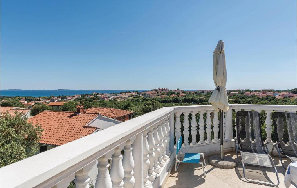 a balcony with a white railing and an umbrella at Beautiful Apartment In Betiga With House Sea View in Barbariga