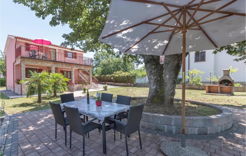 een tafel met stoelen en een parasol op een patio bij Cozy Home In Labin With Kitchen in Labin