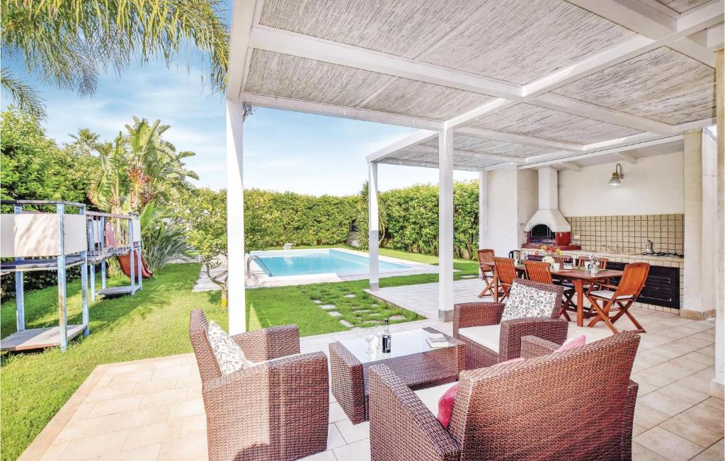 un patio con tavolo, sedie e piscina di Stunning Home In Scicli Rg With Private Swimming Pool, Can Be Inside Or Outside a Donnalucata