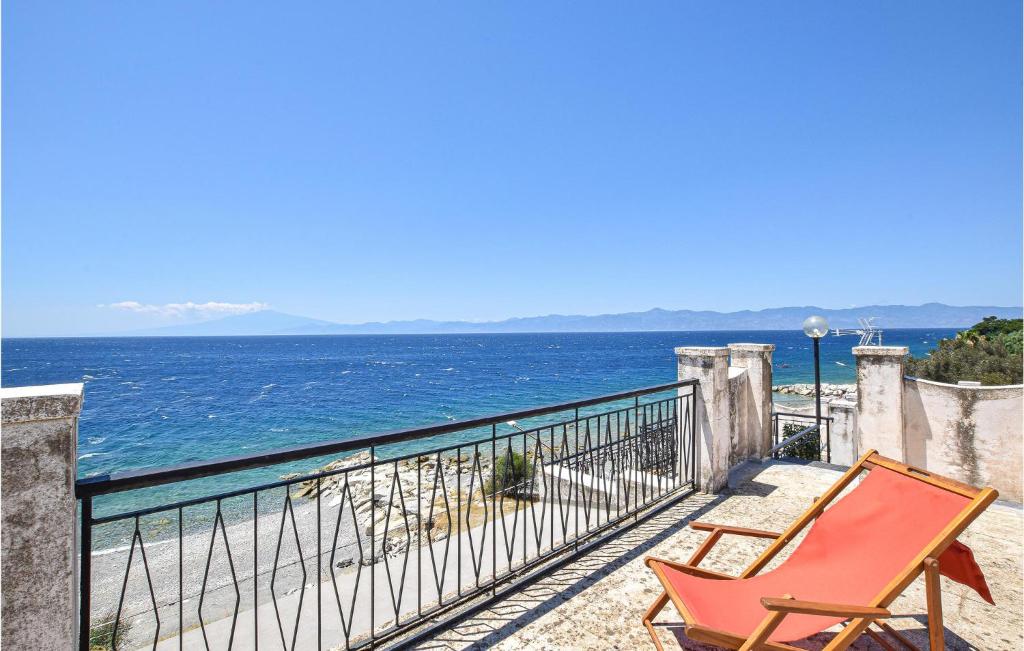 a red chair sitting on a balcony overlooking the ocean at Villa Annamaria in Lazzaro