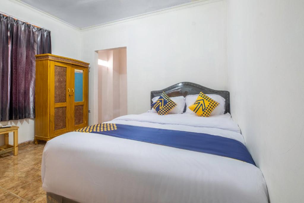 een slaapkamer met een bed met gele en blauwe kussens bij OYO Life 2412 Mandala Residence in Pundong