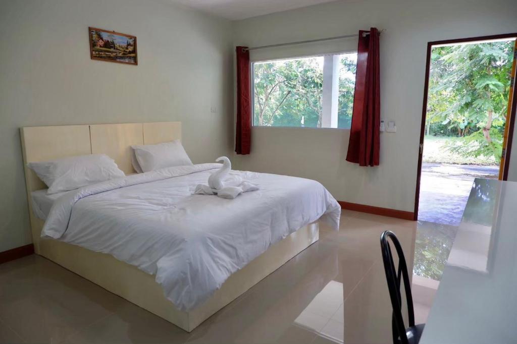 Un dormitorio con una cama blanca con un cisne. en โรงแรมคอมม่อนเวลธ์ Commonwealth Hotel&Resort en Suan Phung