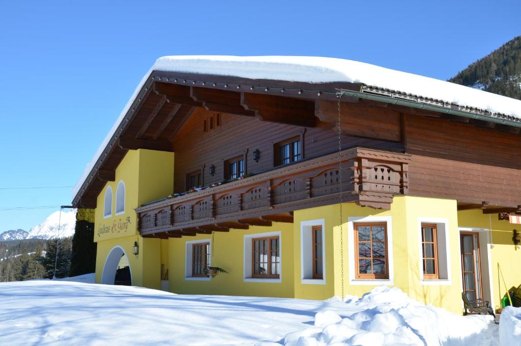 a large building with snow in front of it at Landhaus St. Georg in Sankt Martin am Tennengebirge