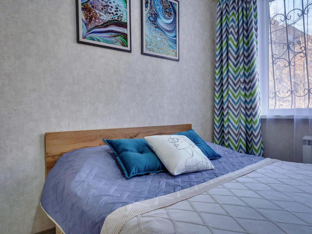 Una cama con almohadas azules y blancas en un dormitorio en YourHouse на Толе би Весновка en Almaty