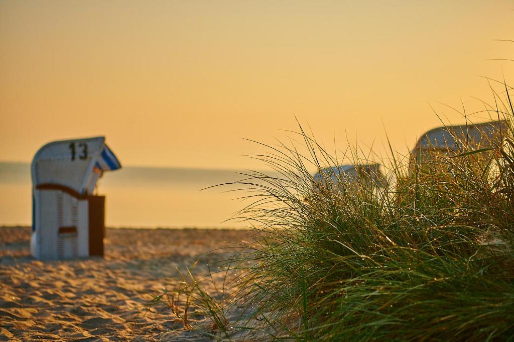 a lifeguard shack on a beach with grass at Strandhotel Fontana in Timmendorfer Strand