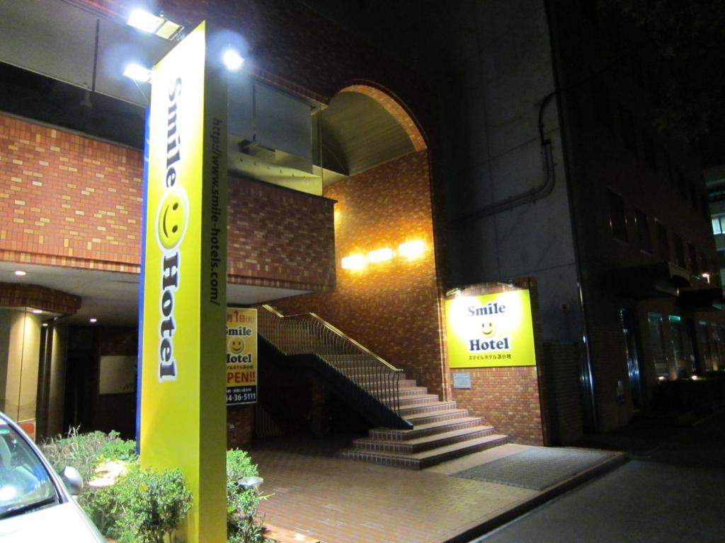 a sign in front of a brick building with stairs at Smile Hotel Tomakomai in Tomakomai