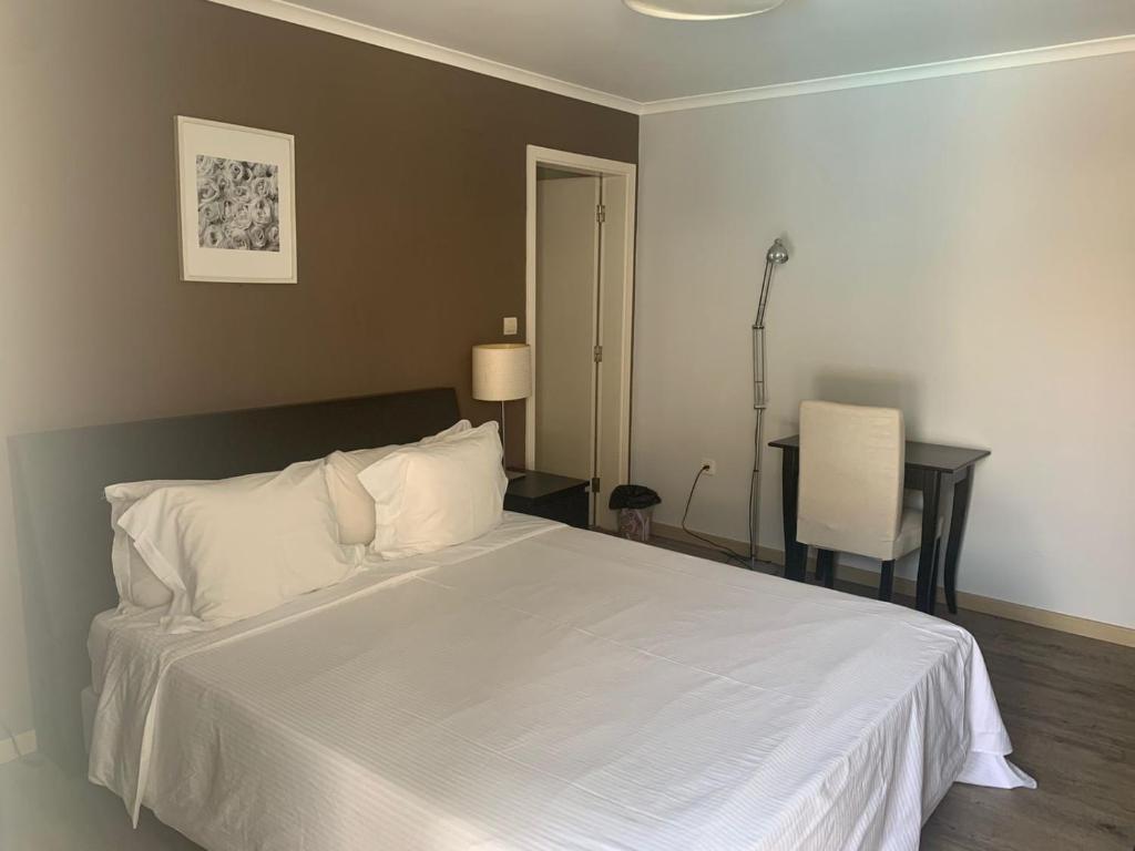 a bedroom with a white bed with a desk and a chair at Casas de Luanda GH-Miramar in Luanda