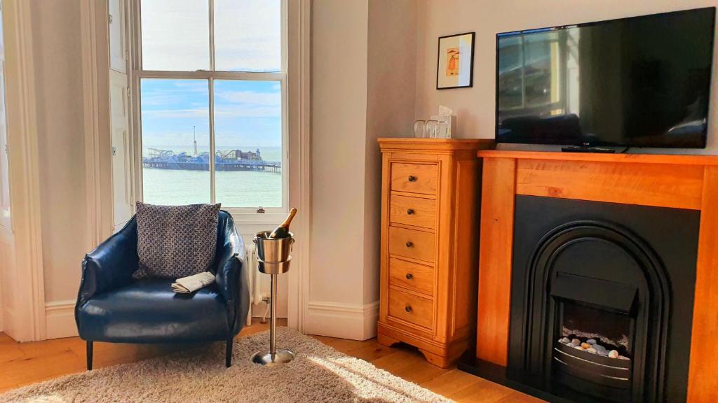 a living room with a fireplace with a television and a chair at A Room With A View in Brighton & Hove