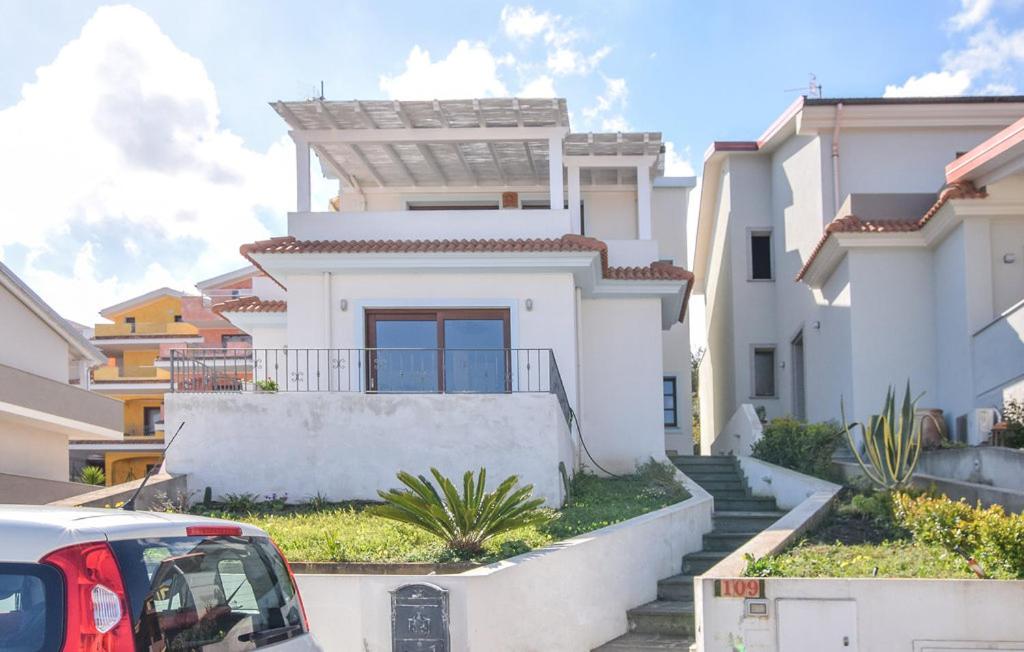 une maison blanche avec une voiture garée devant elle dans l'établissement Casa Gallinelle sarde, à Castelsardo