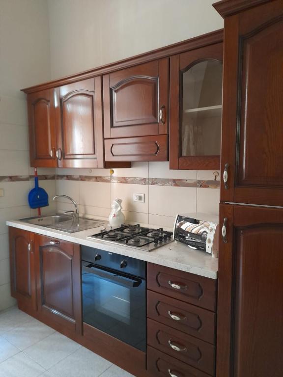 La cuisine est équipée de placards en bois et d'un four avec plaques de cuisson. dans l'établissement Monolocale Foggia Centro, à Foggia