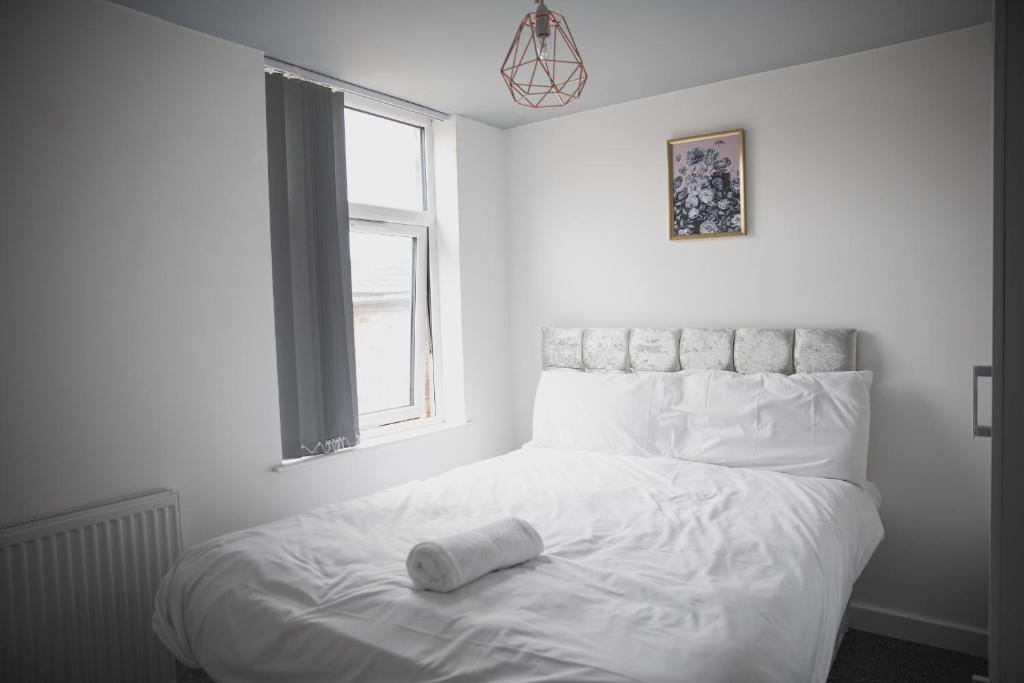 a white bed with a roll on it in a bedroom at Leicester House in Leicester