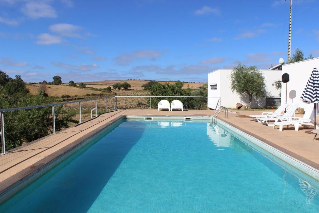 a swimming pool with chairs and a house at Villa Martins in Lagoaça