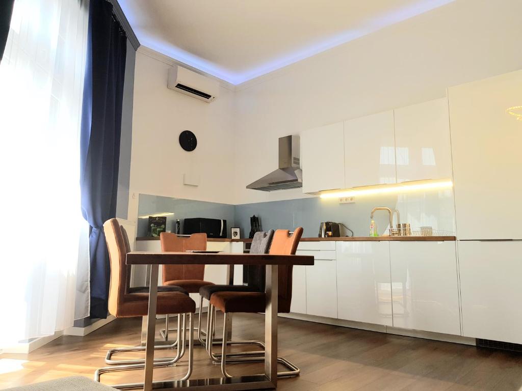 a kitchen with white cabinets and a table and chairs at Luxurious Apartment with Balconies in DownTown BP in Budapest