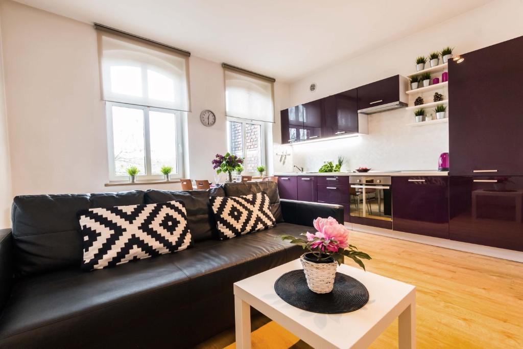 a living room with a black leather couch and a table at LEMON Apart in Katowice