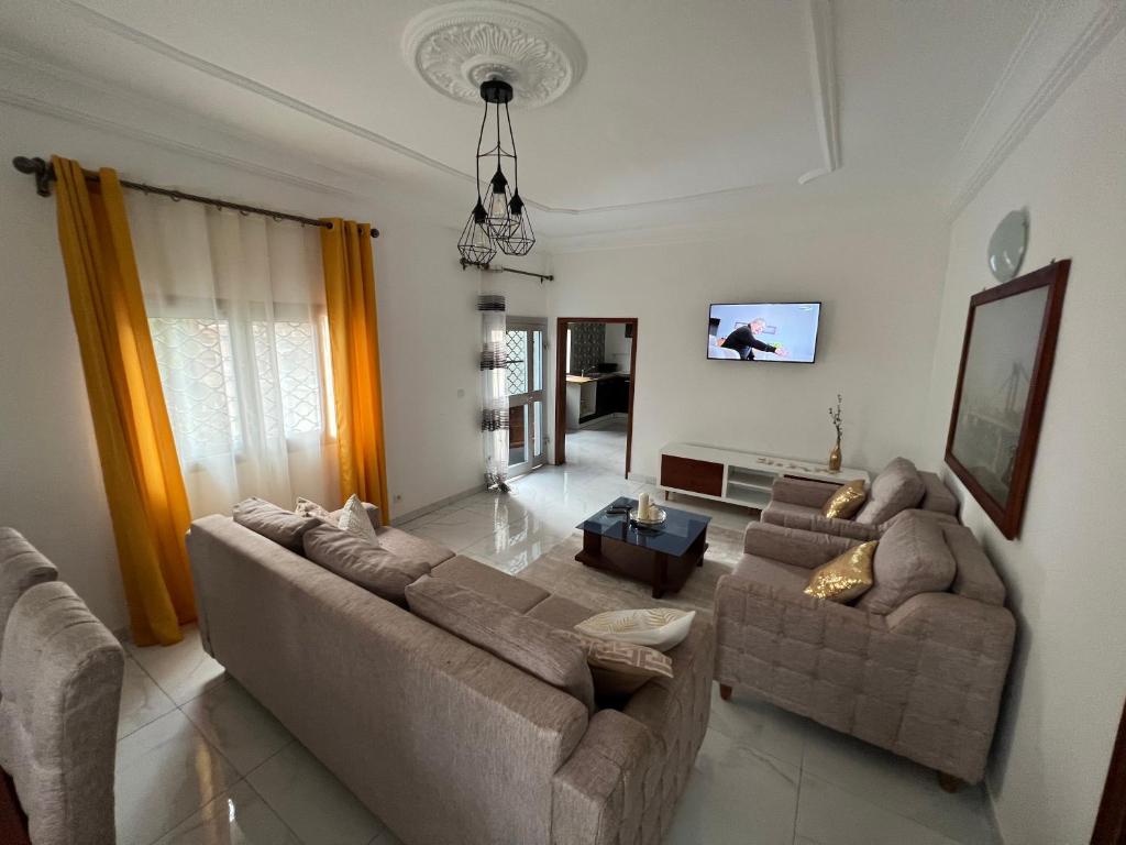 sala de estar con 2 sofás y TV en RÉSIDENCE MEUBLÉE 1ERE CLASSE DOUALA pk 15, en Douala