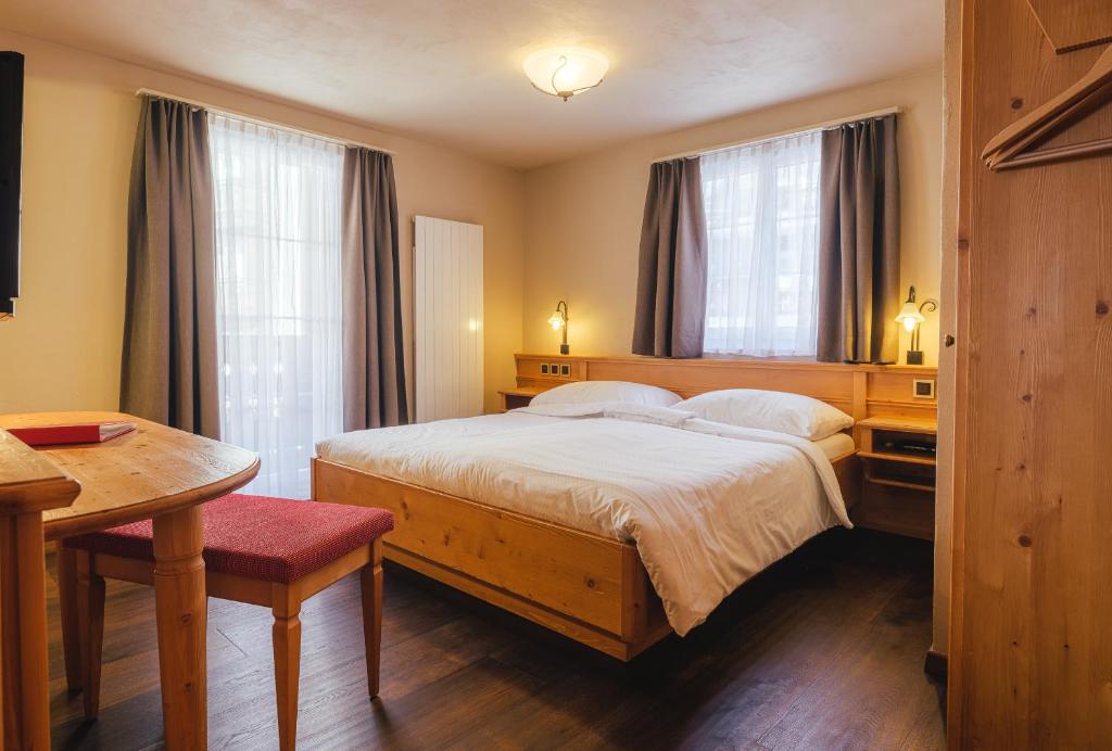 a bedroom with a bed and a table and window at Guesthouse by the rex in Zermatt