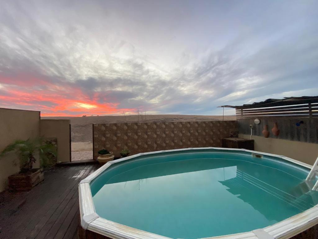 a swimming pool on top of a building with a sunset at Desert Pearl Arad in Arad