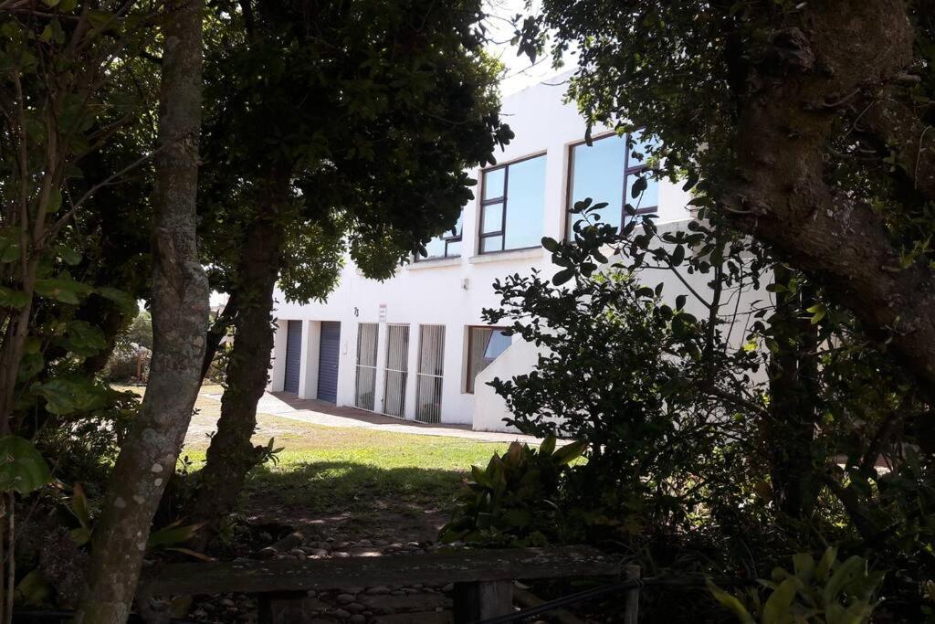 a white building with windows and trees in front of it at The Whitehouse at Oysterbay with dream views in Oyster Bay