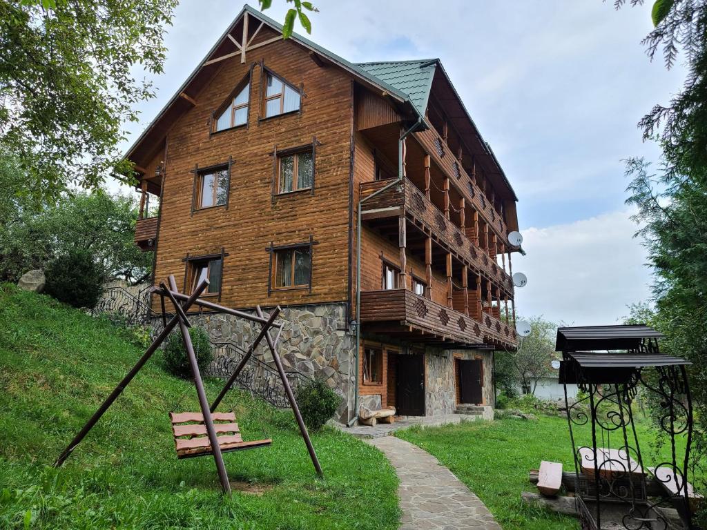 a large wooden house with a playground in front of it at Гуцульська хата in Yaremche