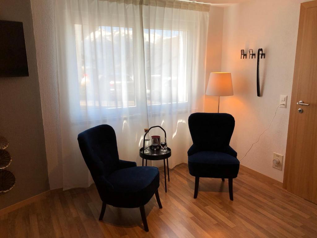 a room with two chairs and a table and a lamp at Wonderful & Private Room with en-suite bathroom in Triesenberg
