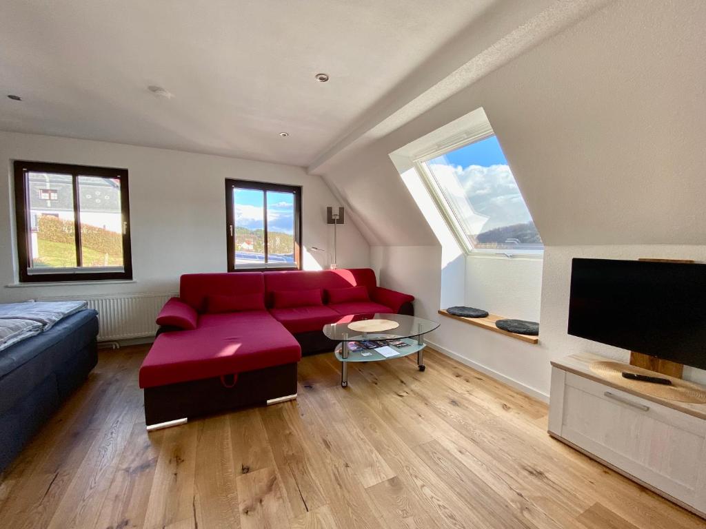 ein Wohnzimmer mit einem roten Sofa und einem Flachbild-TV in der Unterkunft Apartmenthaus RuheZeit in Bad Endbach