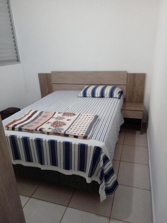 um quarto com uma cama com um cobertor listrado em Apartamento proximo ao shopping Franca em Franca