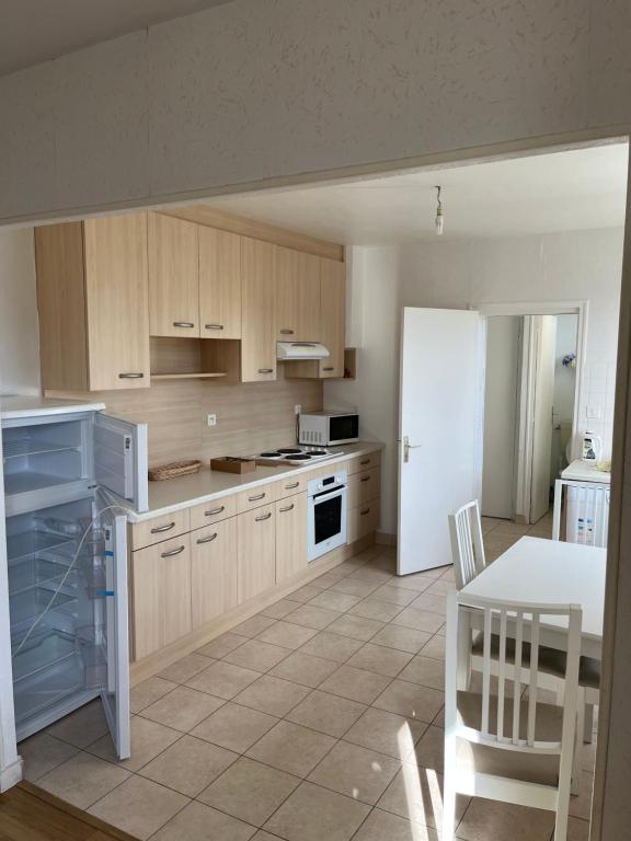 a kitchen with wooden cabinets and a white refrigerator at appartement spacieux et lumineux proche de la plage in Quimiac