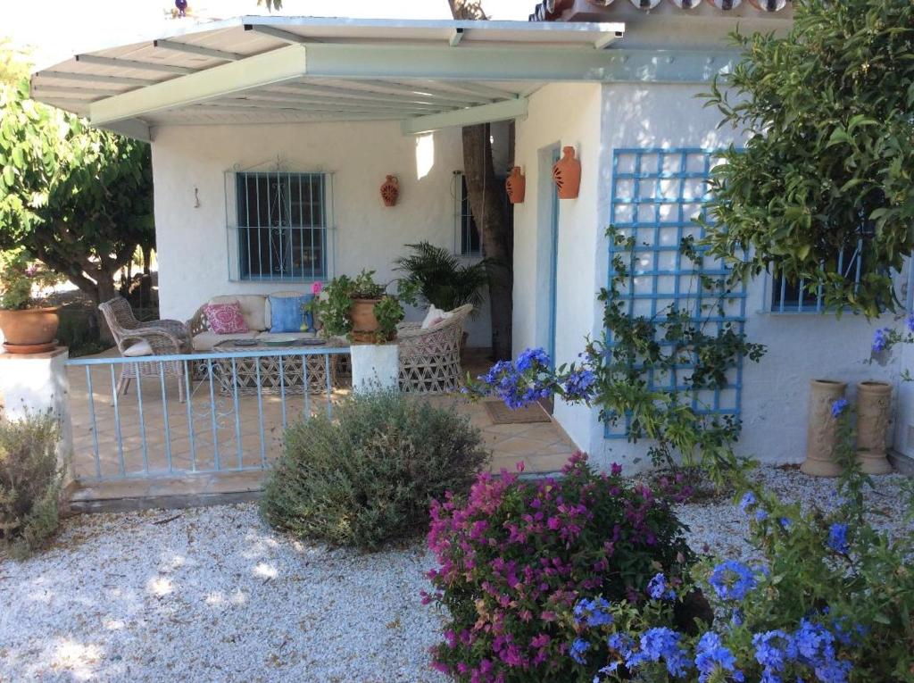 a small white house with a gate and some flowers at Molino Cottage in Estepona