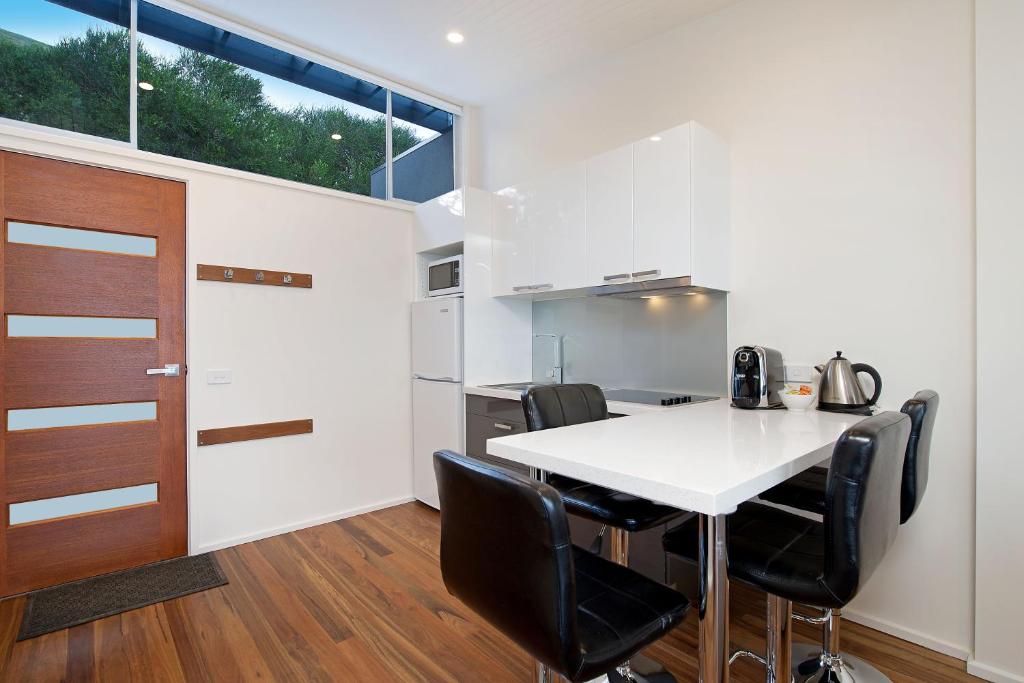 a kitchen with a white table and black chairs at Seafarers Getaway in Apollo Bay