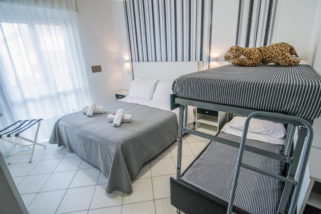 una camera con 2 letti singoli e un letto a castello Sidx Sidx Sidx Sidx di Hotel Mizar a Rimini