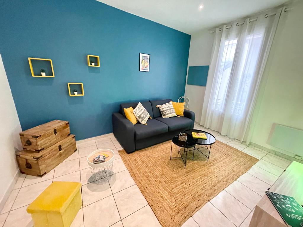 un salon avec un canapé noir et un mur bleu dans l'établissement Joli appartement spacieux à 3 min à pied de la mer, à Nice