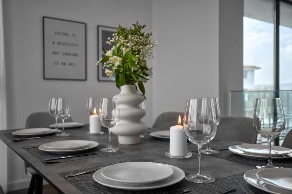 a dining table with glasses and candles and a vase with flowers at The Penthouse in Ahtopol