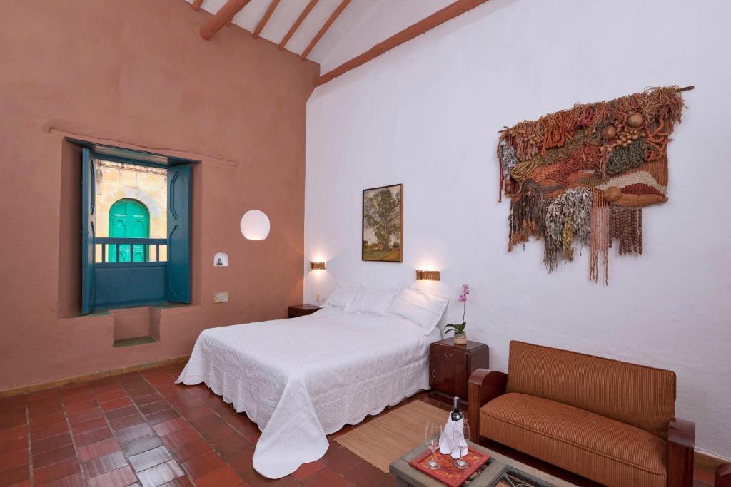 um quarto com uma cama, um sofá e uma janela em Posada del Campanario em Barichara