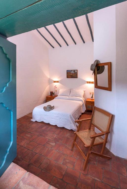 a bedroom with a bed and a chair at Posada del Campanario in Barichara