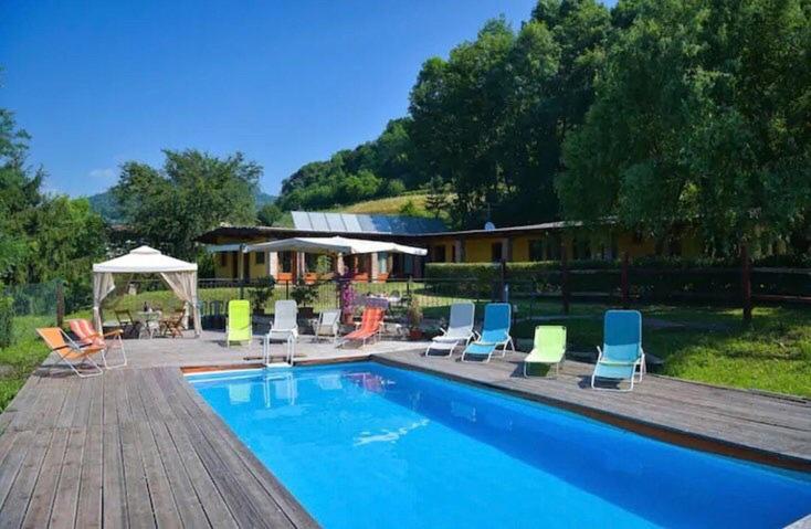 une piscine avec des chaises longues et une maison dans l'établissement LA POIANA, à Pignerol