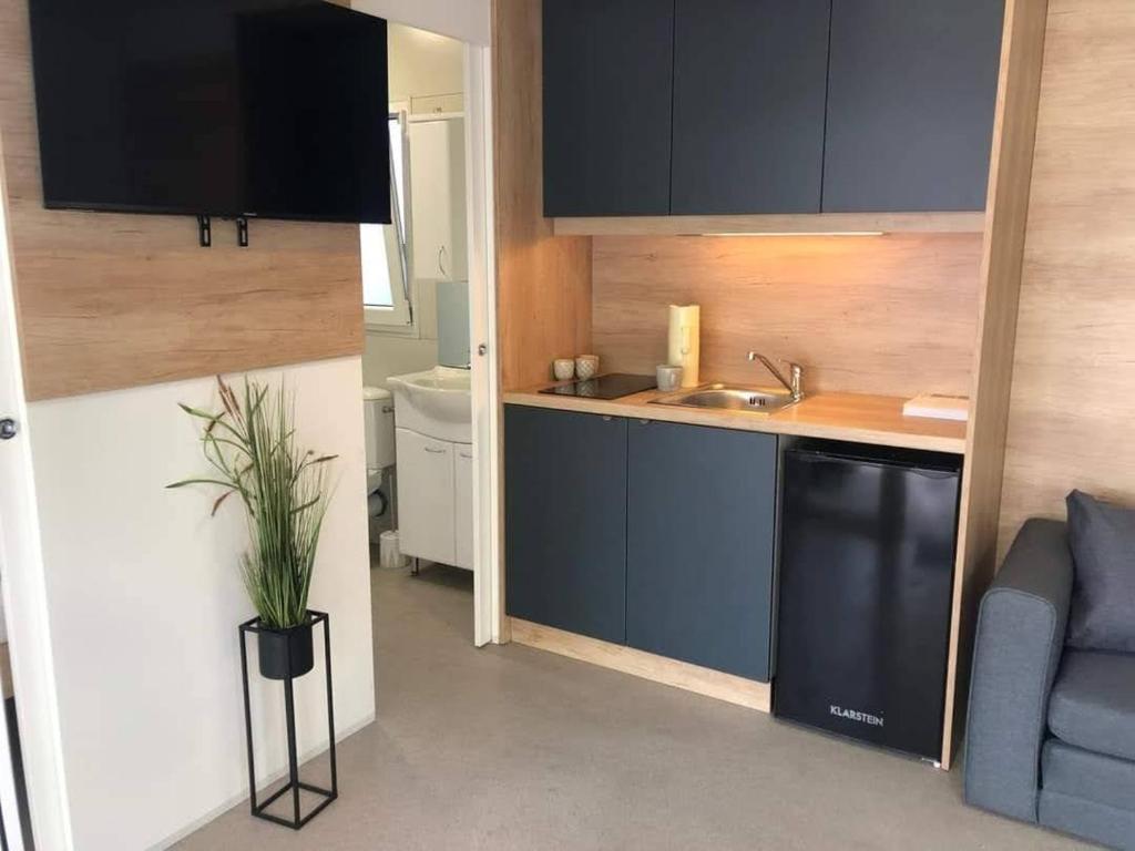 a kitchen with blue cabinets and a sink and a couch at M&M Mobile home in Privlaka