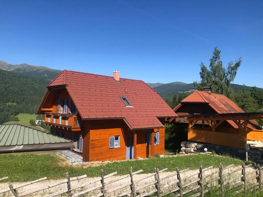 una casa con tetto rosso accanto a una recinzione di St Wolfgang-Kienberg - Ruhe und Entspannung mit bester Aussicht a Obdach