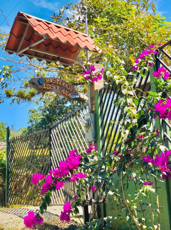 ein Straßenschild mit rosa Blumen vor einem Zaun in der Unterkunft Hospedaje Luis & Ana in Pejibaye