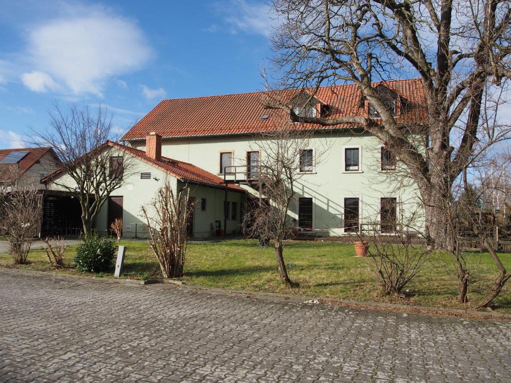 Una casa blanca con un árbol delante. en Altes Teichhaus - Pension Ottendorf-Okrilla, en Ottendorf-Okrilla