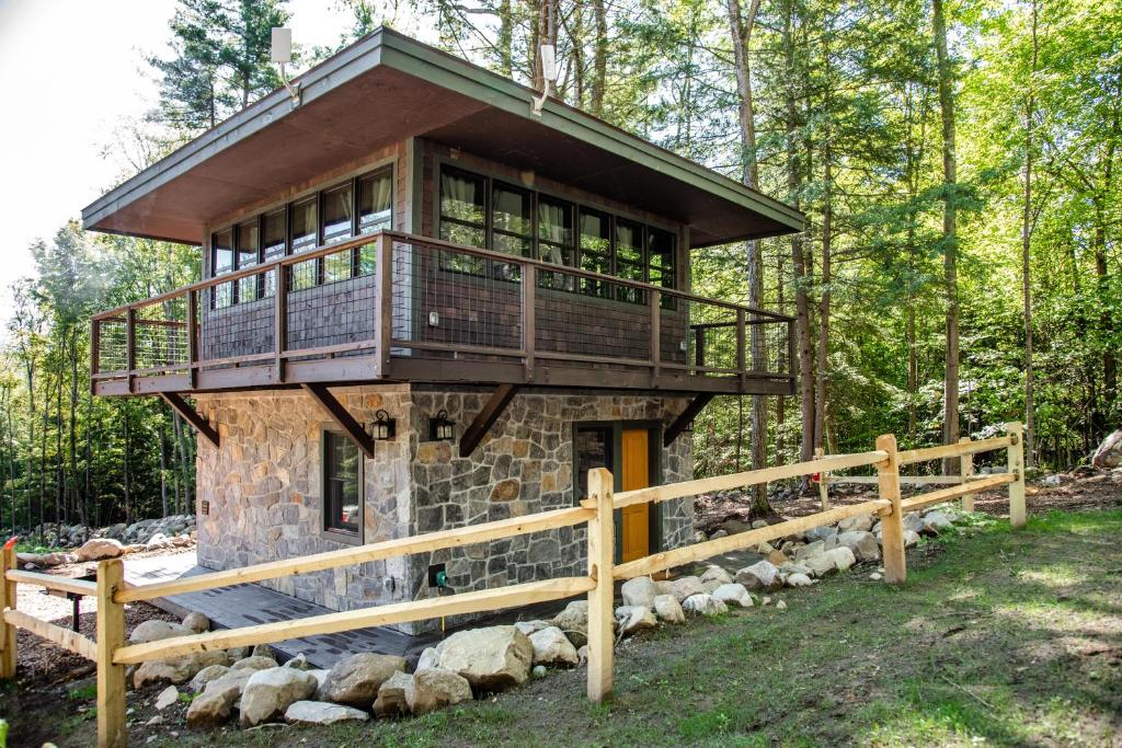 a tree house in the woods with a balcony at Trekker, Treehouses cabins and lodge rooms in Lake George