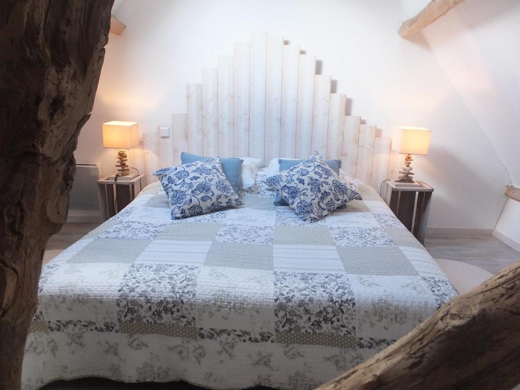 - une chambre avec un grand lit et des oreillers bleus dans l'établissement Les gîtes de "La Quesnoyère", à Quesnoy-le-Montant