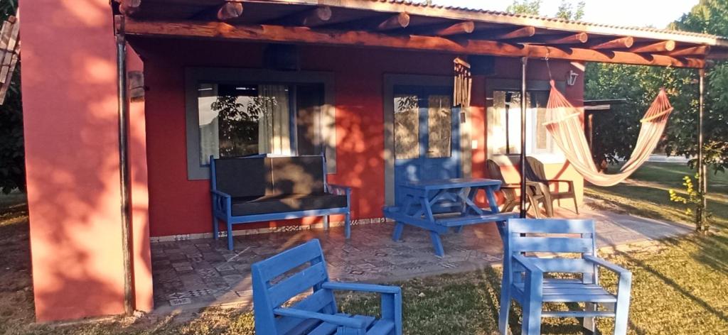 a red house with blue chairs and a swing at Cabaña Gota de Rocio en finca Margarita in San Rafael