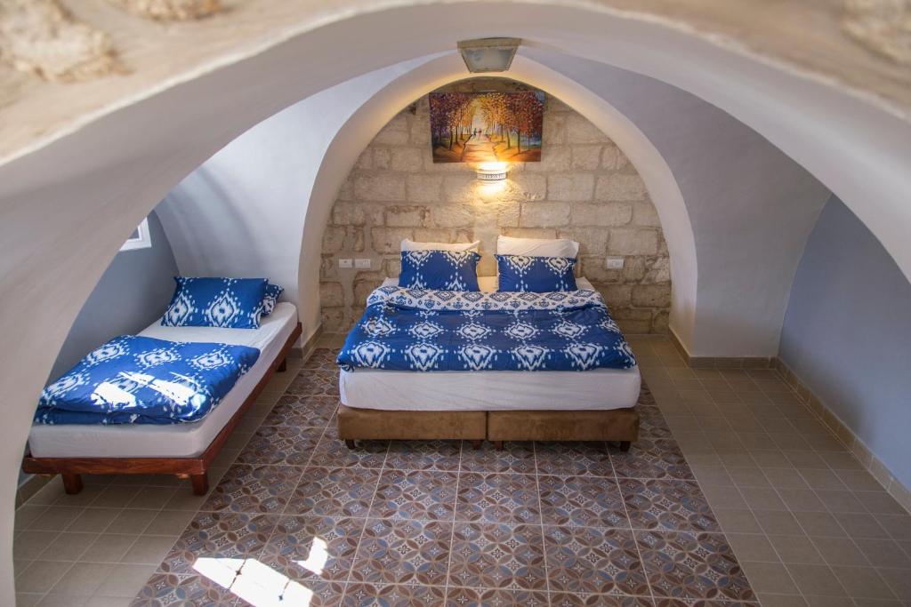 two beds in a room with an archway at Alexandra House in Nazareth