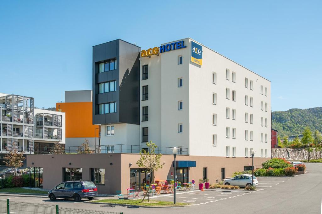 un edificio de hotel con coches aparcados en un aparcamiento en Ace Hotel Annecy en Annecy