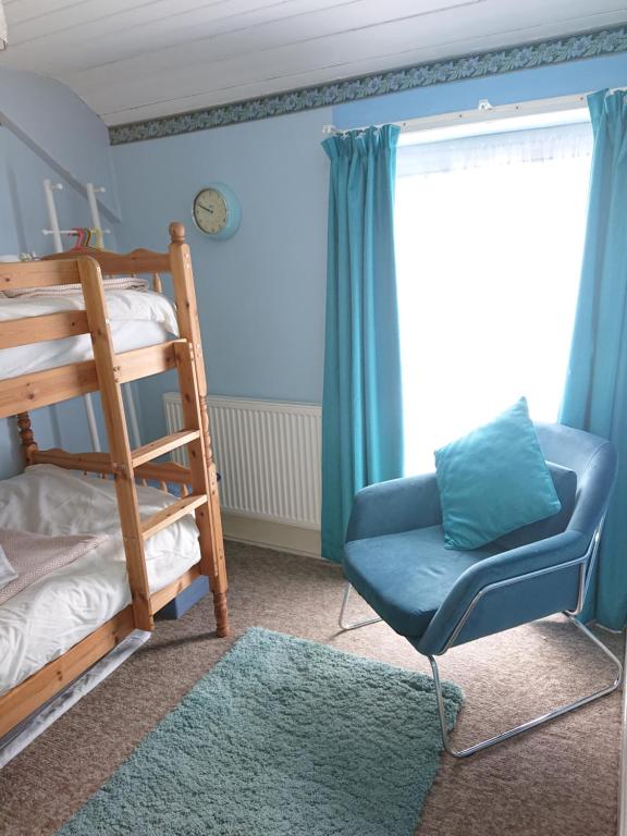 a blue room with a chair and a bunk bed at 2 Bed Cottage Dog Child Friendly 15min walk to beach in Ederyn